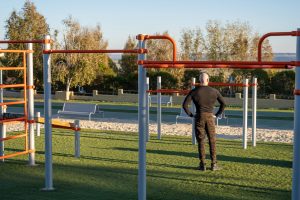A back view of a young Hispanic man having a rest after working out in the sports ground
